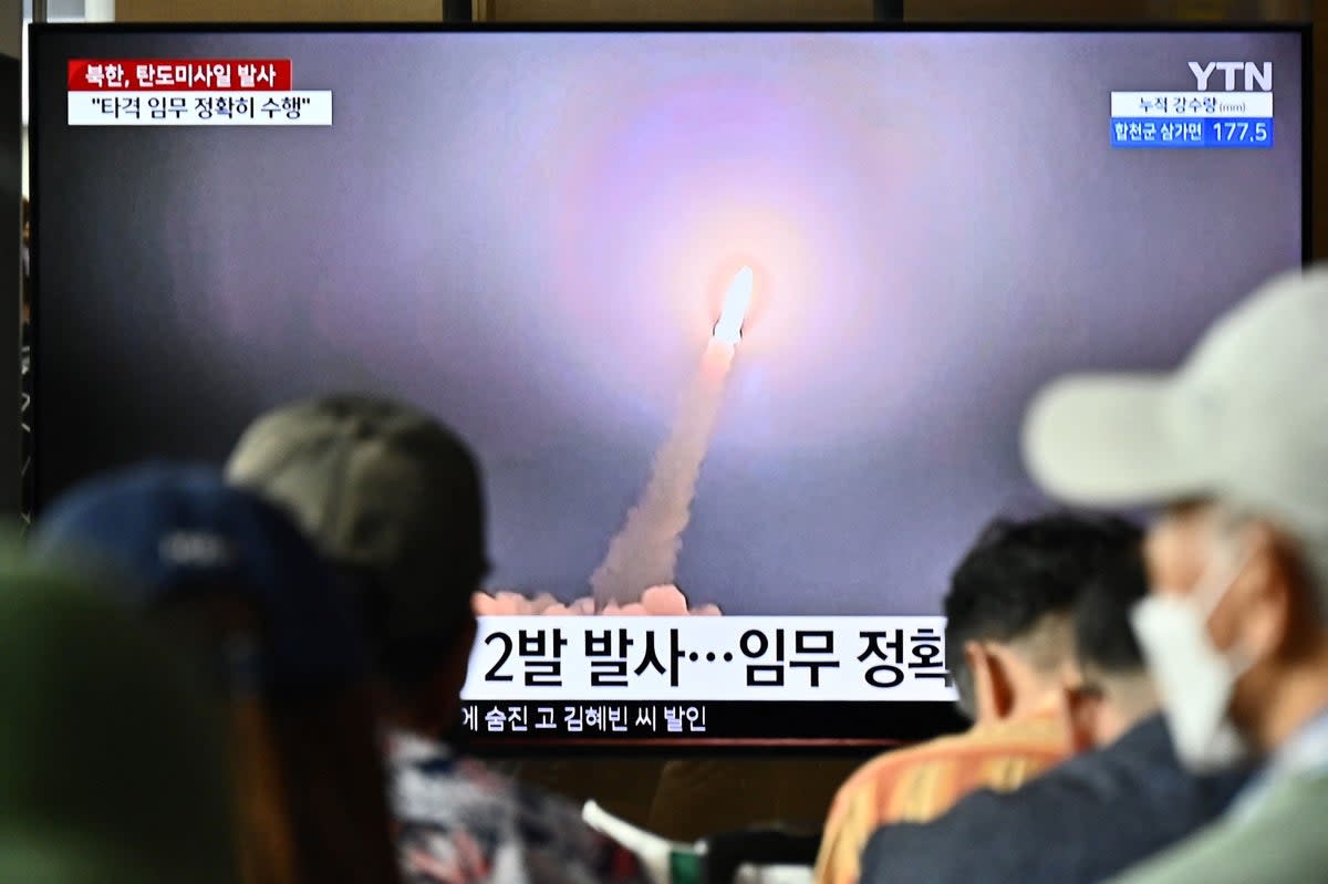 People watch a television showing a news broadcast with a photo of a North Korean missile test on 31 August (AFP via Getty Images)