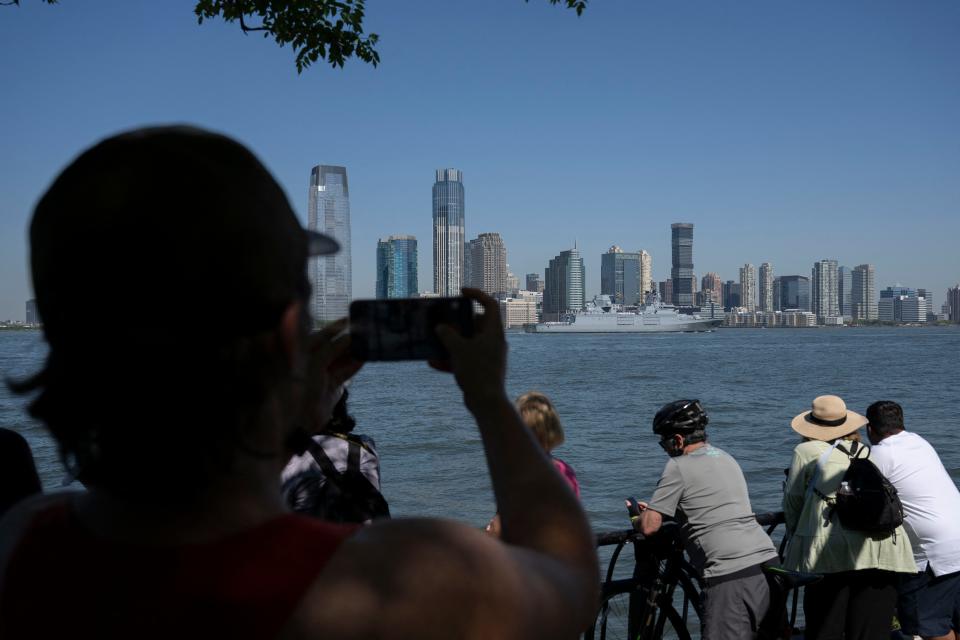 People take photos as the Baden-Württemberg-class frigate lead ship of the German Navy passes during Fleet Week in New York Harbor on May 22, 2024.