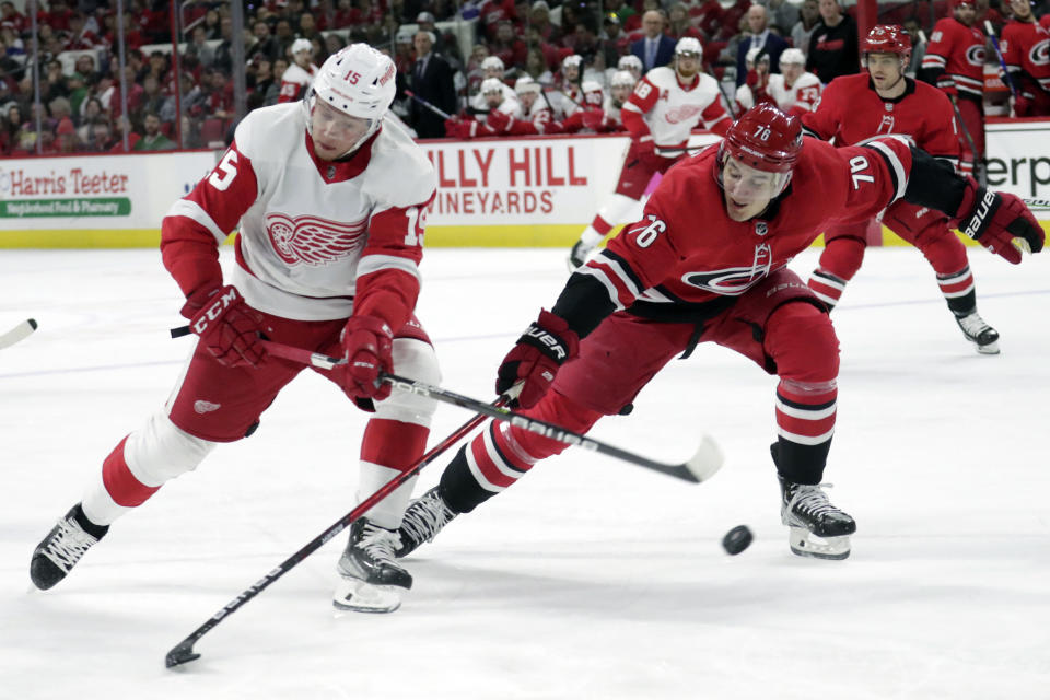 Detroit Red Wings left wing Jakub Vrana (15) and Carolina Hurricanes defenseman Brady Skjei (76) vie for the puck during the first period of an NHL hockey game Thursday, April 14, 2022, in Raleigh, N.C. (AP Photo/Chris Seward)