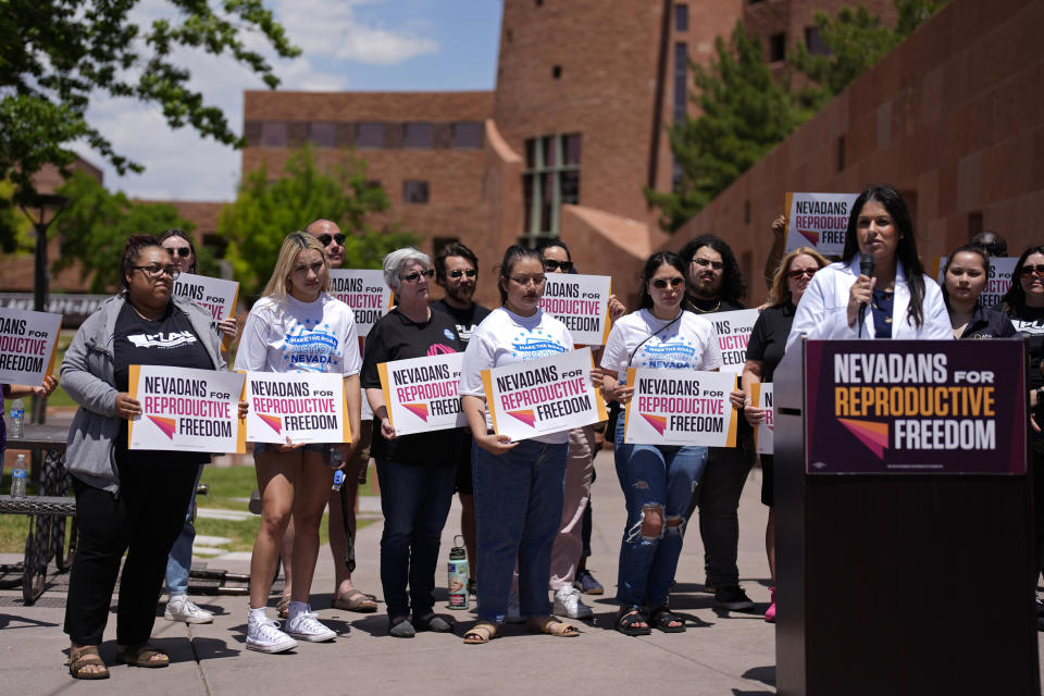 People hold signs during a news conference by Nevadans for Reproductive Freedom, Monday, May 20, 2024, in Las Vegas. Abortion access advocates in Nevada said Monday they've submitted twice the number of petition signatures needed to qualify for a ballot measure aimed at enshrining what they term reproductive rights in the state constitution. (AP Photo/John Locher)