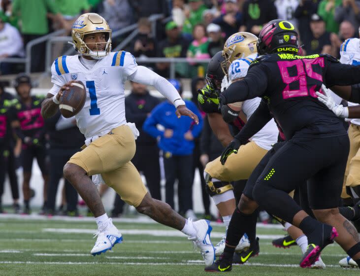 UCLA 's Dorian Thompson-Robinson, left, runs out of the pocket under pressure from the Oregon defense.