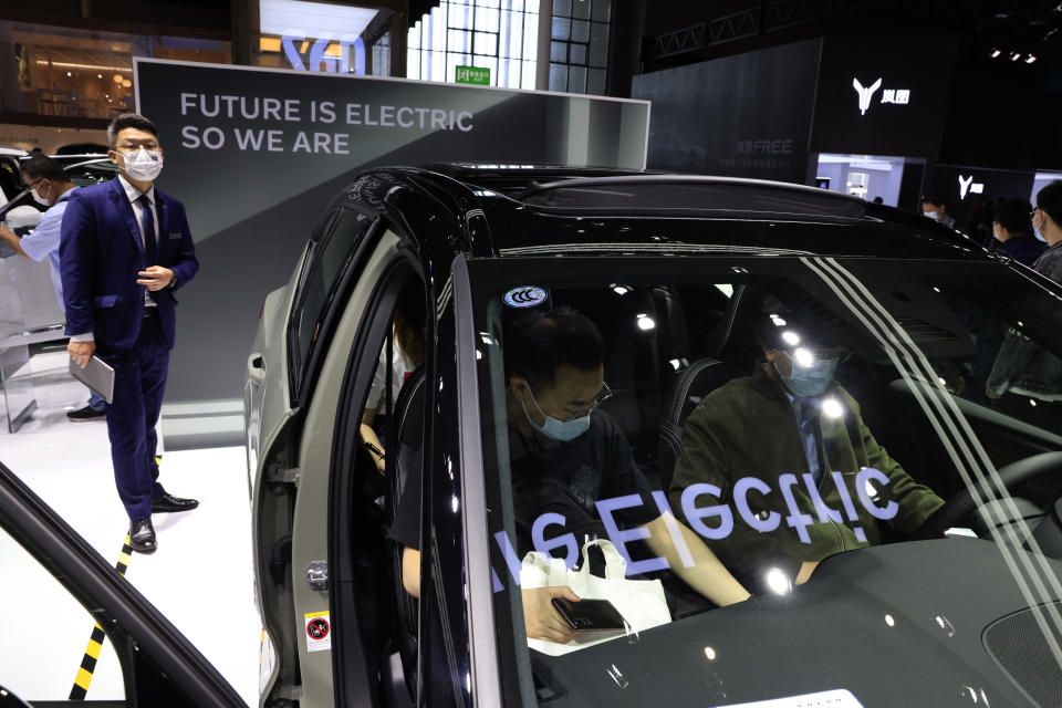 FILE - A promoter stands near the all-electric Volvo XC40 during the Shanghai Auto Show in Shangha, in this Wednesday, April 21, 2021, file photo. Global automakers are stepping up the pace when it comes to building factories to prepare for what many believe will be a fast-moving transition from internal combustion engines to electric vehicles. On Monday, Oct. 18, 2021, Toyota, Stellantis, Foxconn, Ford and Volvo all made announcements about electric vehicle component or assembly plants, or plans to raise capital to fund the transition.(AP Photo/Ng Han Guan, File)