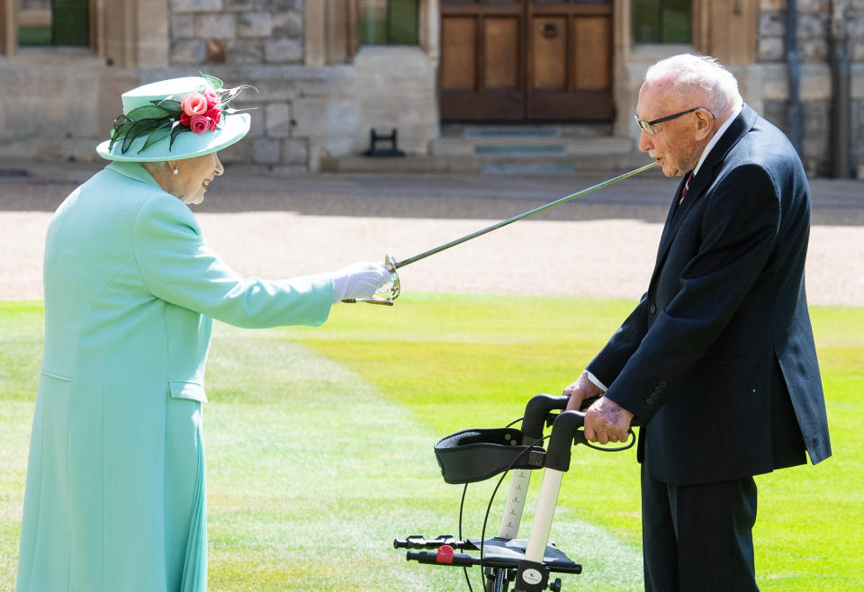 WINDSOR, ENGLAND - JULY 17: Queen Elizabeth II (using the sword that belonged to her father, King George VI) confers the Honour of Knighthood on Captain Sir Thomas Moore before presenting him with the insignia of Knight Bachelor during an investiture ceremony at Windsor Castle on July 17, 2020 in Windsor, England.  British World War II veteran Captain Tom Moore raised over £32 million for the NHS during the coronavirus pandemic.  (Photo by Pool/Samir Hussein/WireImage)