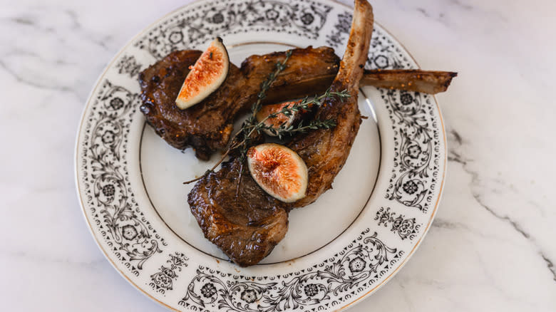 A plate with two lamb chops with figs and thyme