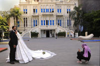 A woman takes pictures of a Lebanese bride and groom in the courtyard of the Sursock Museum, which was damaged in the explosion last August at Beirut's port, in Beirut, Lebanon, Lebanon's only modern art museum, the Sursock, is still rebuilding a year after the explosion decimated it and some hope that reopening it will be a first step in the harder task of rebuilding the city's once thriving arts scene. (AP Photo/Hussein Malla)