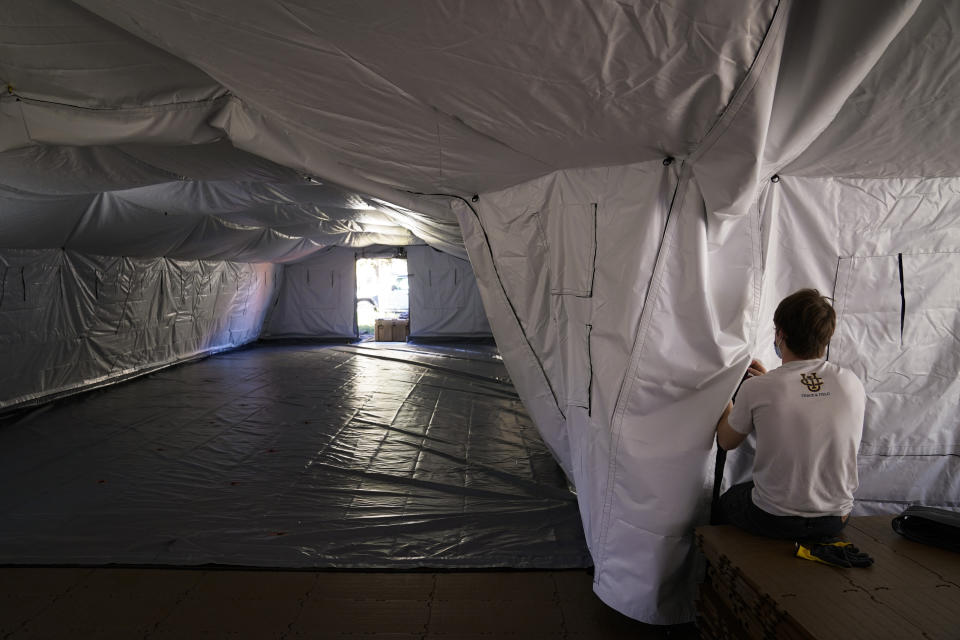 A volunteer works in a mobile field hospital at UCI Medical Center, Monday, Dec. 21, 2020, in Orange, Calif. California's overwhelmed hospitals are setting up makeshift extra beds for coronavirus patients, and a handful of facilities in hard-hit Los Angeles County are drawing up emergency plans in case they have to limit how many people receive life-saving care. (AP Photo/Jae C. Hong)