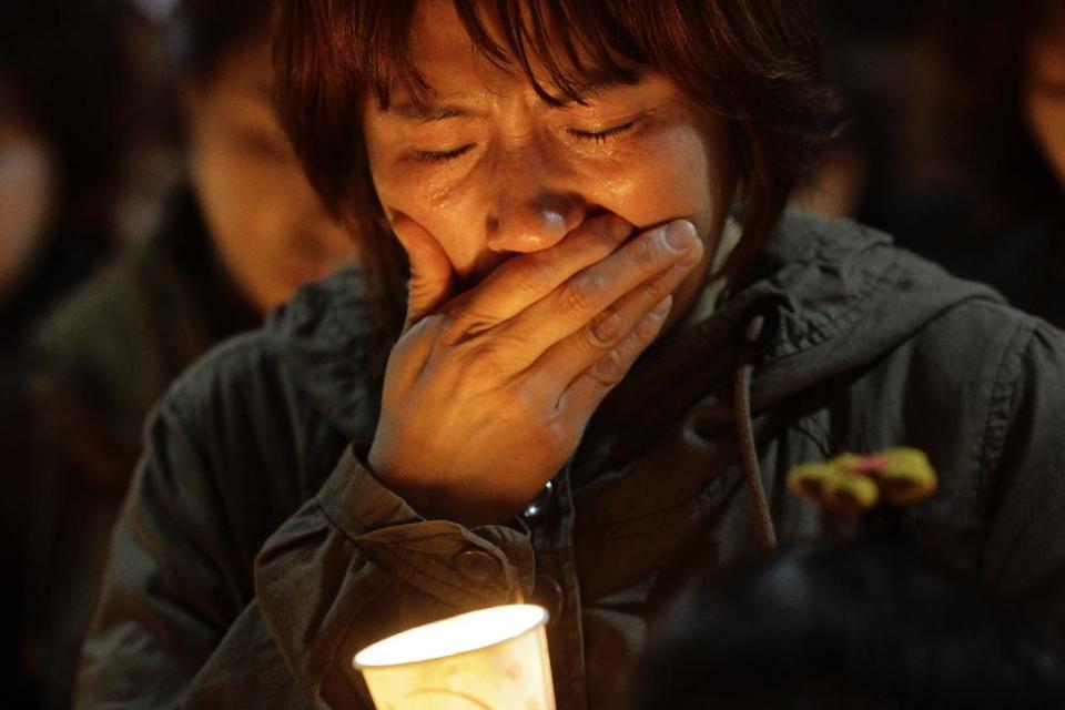 A woman offers prayers during a candlelight vigil for the missing passengers of a sunken ferry at Danwon High School in Ansan, South Korea, Thursday, April 17, 2014. An immediate evacuation order was not issued for the ferry that sank off South Korea's southern coast, likely with scores of people trapped inside, because officers on the bridge were trying to stabilize the vessel after it started to list amid confusion and chaos, a crew member said Thursday. (AP Photo/Wonghae Cho)