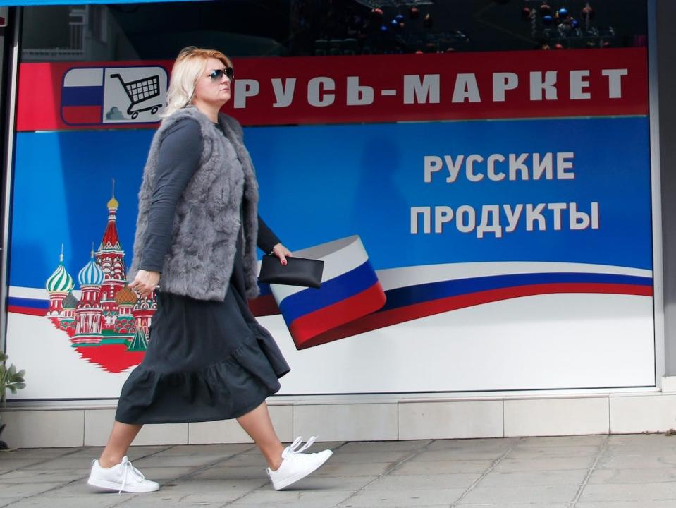 A woman walks past a Russian supermarket in the Cypriot port city of Limassol, Cyprus.