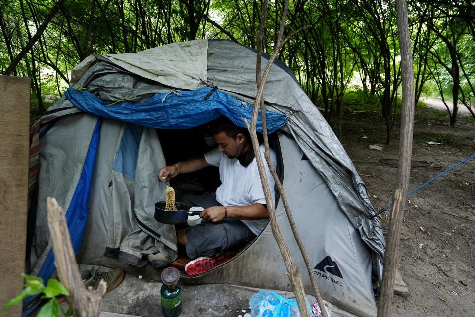 Jay Chindavong prepares noodles for himself and Connie Phongchomphet on Monday at a homeless camp near the Scioto River on the Far South Side that is not facing immediate eviction by the city of Columbus, unlike the one the city plans to clear near Heer Park on June 14.