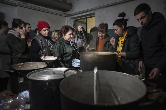 A woman ladles out hot food for people in line at a bomb shelter in Mariupol.