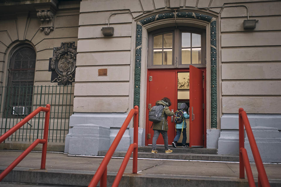 A migrant child, right, who lives at the Row Hotel, enters his school together with a classmate on Tuesday, Dec. 12, 2023, in New York. It could be a cold, grim New Year for thousands of migrant families living in New York City’s emergency shelter system. With winter setting in, they are being told they need to clear out, with no guarantee they’ll be given a bed elsewhere. (AP Photo/Andres Kudacki)