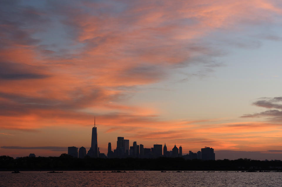 JERSEY CITY, NJ - OCTOBER 16: The sun rises behind lower Manhattan and One World Trade Center in New York City on October 16, 2021 as seen from Jersey City, New Jersey. (Photo by Gary Hershorn/Getty Images)