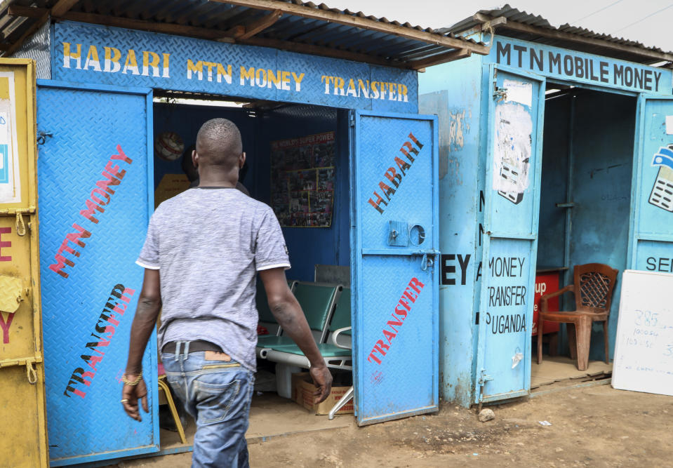 In this photo taken Tuesday, Sept. 10, 2019, a man walks past several mobile money kiosks in the capital Juba, South Sudan. South Sudan has launched mobile money, the ability to send and receive funds by phone, in an attempt to boost the economy after a five-year civil war killed almost 400,000 people. (AP Photo/Sam Mednick)