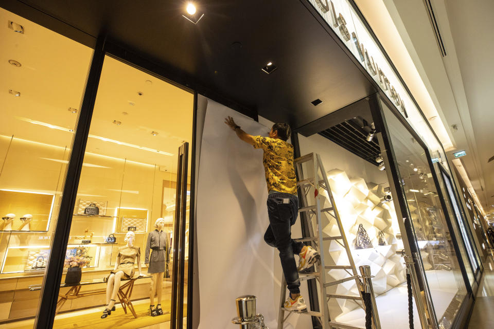 A worker covers a door damaged by a bullet at a shopping mall in Bangkok, Thailand, Wednesday, Oct. 4, 2023. A teenage boy with a handgun opened fire inside the major shopping mall Tuesday afternoon, killing a few people before being apprehended, authorities said. (AP Photo/Wason Wanichakorn)