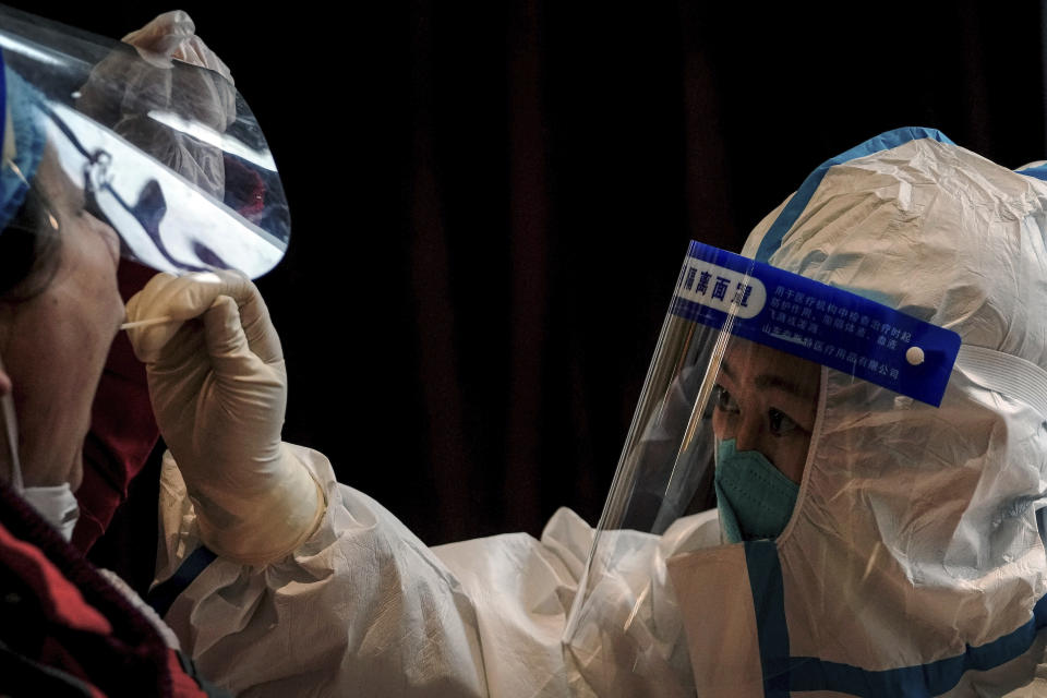 A health worker in protective suit takes a throat swab sample from a worker at a coronavirus testing site inside a hotel used for people who worked at the 2022 Winter Paralympics to stay during a period of health quarantine, Thursday, March 17, 2022, in the Yanqing district of Beijing. A fast-spreading variant known as "stealth omicron" is testing China’s zero-tolerance strategy, which had kept the virus at bay since the deadly initial outbreak in the city of Wuhan in early 2020. (AP Photo/Andy Wong)