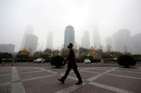 FILE PHOTO - A man wearing a mask walks in the central business district on a polluted day after a yellow alert was issued for smog, in Beijing, China November 14, 2018. REUTERS/Jason Lee/File Photo