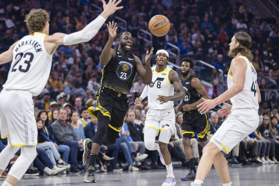 Golden State Warriors forward Draymond Green, second from left, passes the ball past Utah Jazz forward Lauri Markkanen, left, and forward Kelly Olynyk (41) during the first half of an NBA basketball game in San Francisco, Friday, Nov. 25, 2022. (AP Photo/John Hefti)