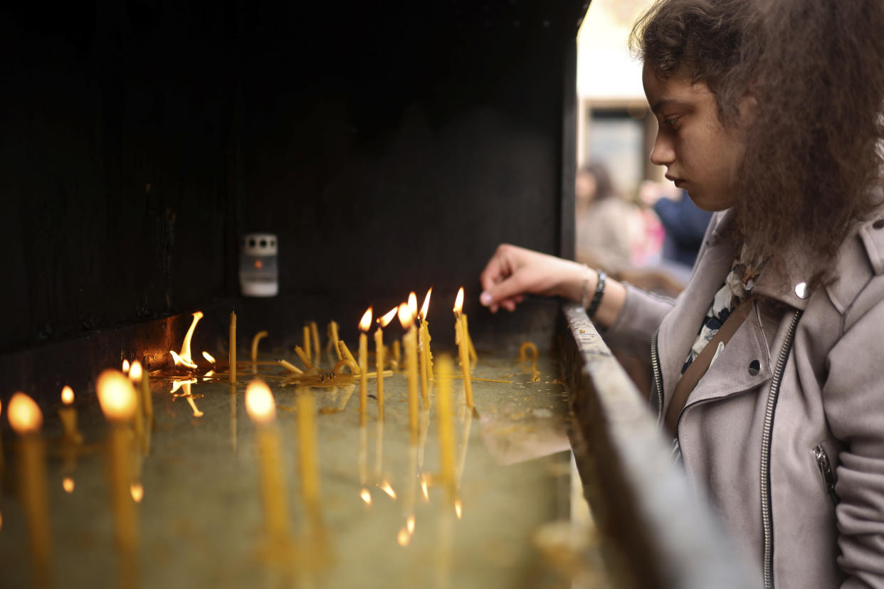 A woman lights candles in front of the St. Sava Serbian Orthodox temple in Belgrade, Serbia, Thursday, May 4, 2023. Hundreds of citizens gathered to pray for the victims, after a 13-year-old on Wednesday killed eight fellow students and a guard. (AP Photo/Armin Durgut)