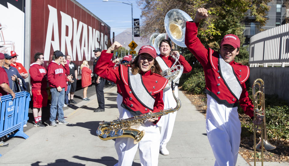 PROVO UT- OCTOBER 15: Band members Grace Leininger, saxophone, and Ethan Thompson, trombone, of the Arkansas Razorbacks cheer with fans as they arrive at LaVell Edwards Stadium before their game against the Brigham Young Cougars October 15, 2022 LaVell Edwards Stadium in Provo, Utah. (Photo by Chris Gardner/ Getty Images)