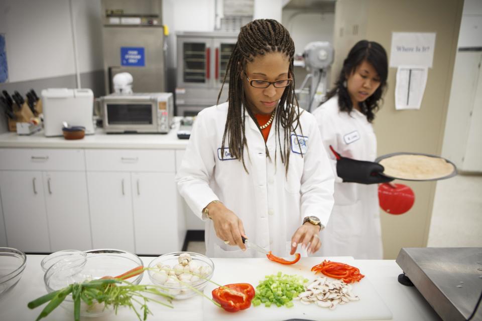 Lockeed Martin research scientist Maya Cooper, left, and Monica Leong, right, prepare a vegan pizza at NASA's Advanced Food Technology Project at Johnson Space Center Tuesday, July 3, 2012, in Houston. NASA is currently planning a mission to Mars, which has gravity, so more options for food preparation, like chopping vegetables, are available as opposed to the dehydrated fare of current space missons. (AP Photo/Michael Stravato)