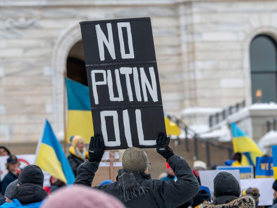 A protestor holding up a signboard "No Putin Oil" among Ukraine flags