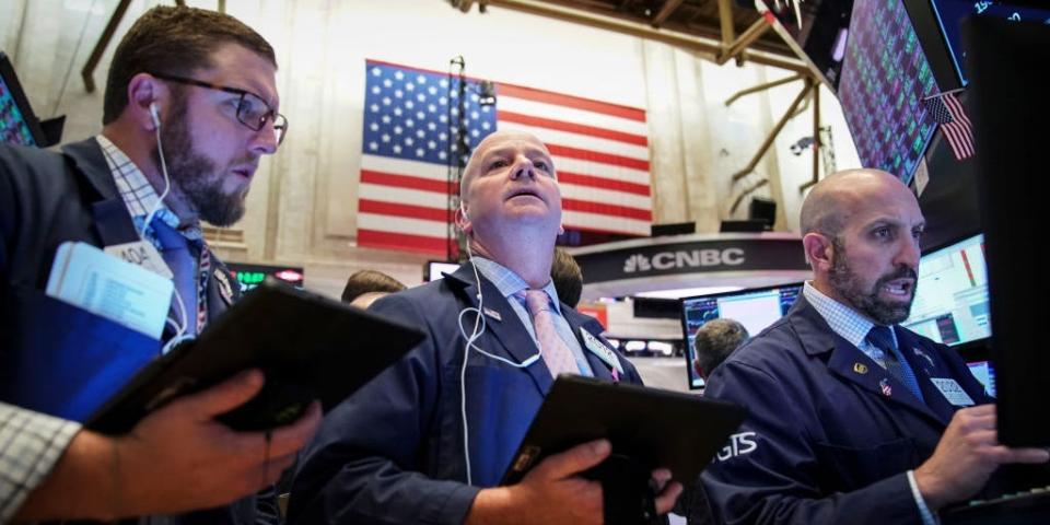 An American flag hangs behind traders working on the floor of the New York Stock Exchange (NYSE) on October 11, 2019 in New York City.