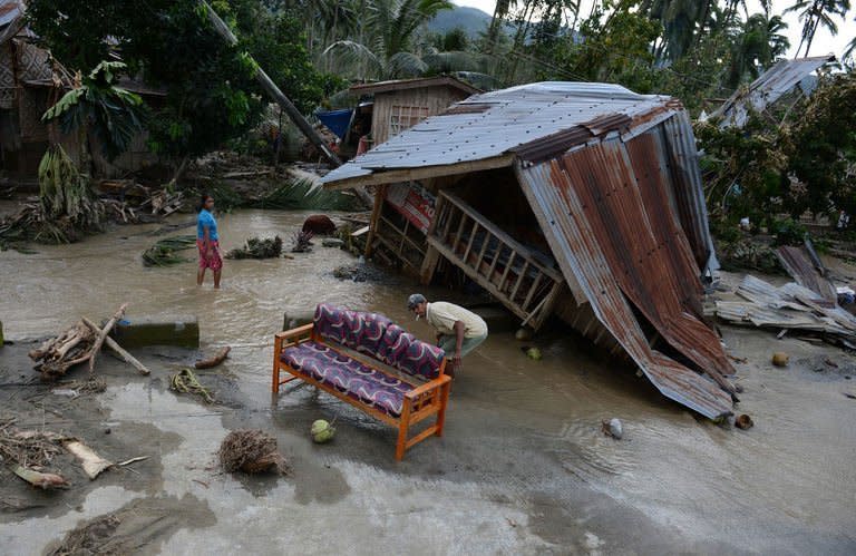 Residents clean up next to their damaged house in New Bataan town on December 5. Manila has appealed for international assistance after a deadly typhoon killed 477 people left a quarter of a million homeless