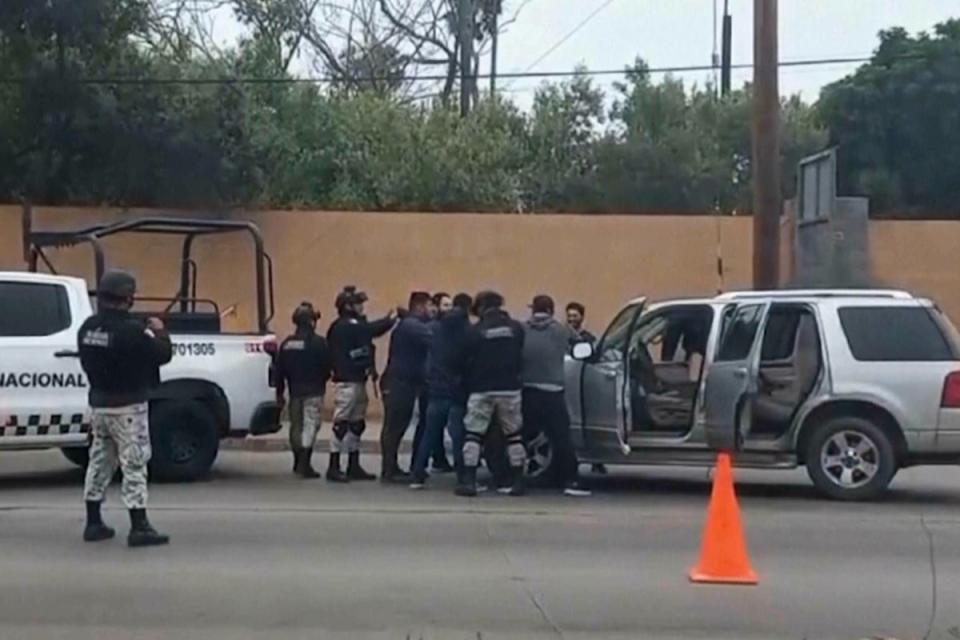 Mexican security forces frisk men at a checkpoint in Ensenada on 2 May 2024. Mexican authorities said Thursday they have found tents and questioned a few people in the case of two Australians and an American who went missing over the weekend in the Pacific coast state of Baja California (AP)