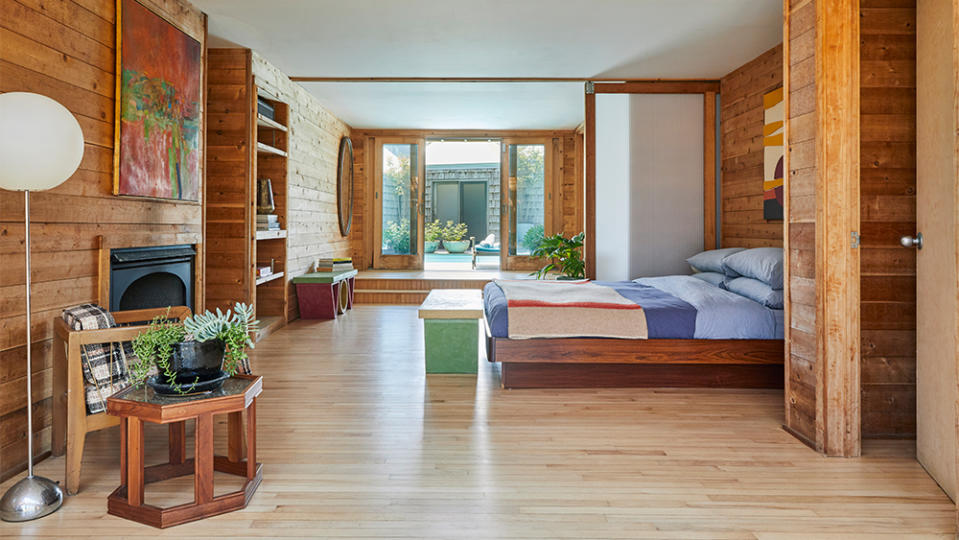 A wood-lined, modern furniture-filled bedroom.