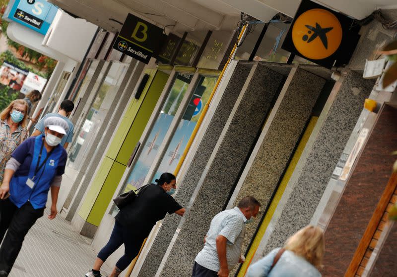 People walk past branches of Bankia and Caixabank in Barcelona