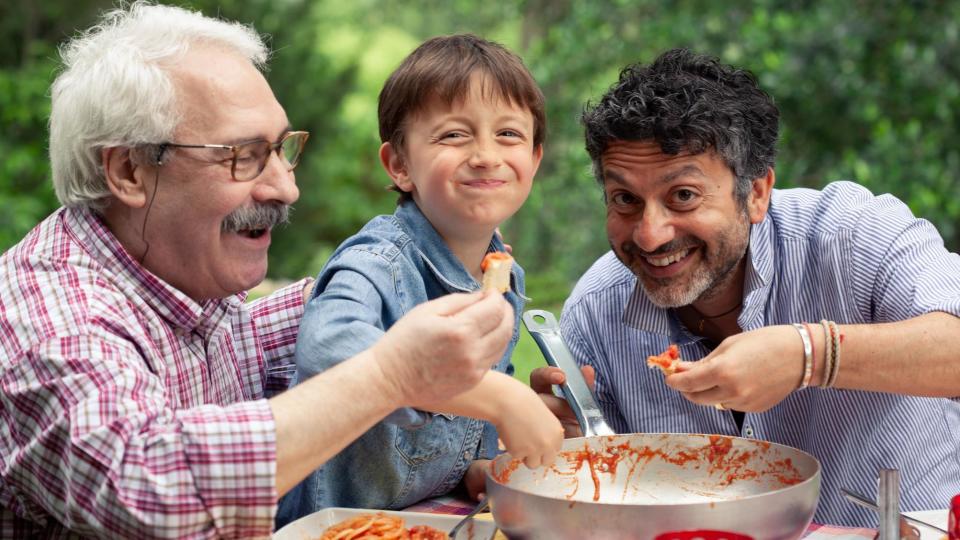 Un niño y dos señores comiendo