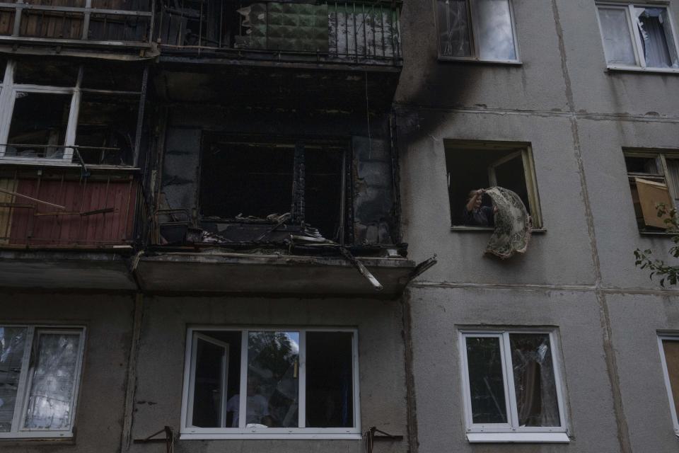 A woman salvages what she can from her damaged apartment, after a rocket hit her five-story residential building, in Kramatorsk, eastern Ukraine, Tuesday, July 19, 2022. (AP Photo/Nariman El-Mofty)