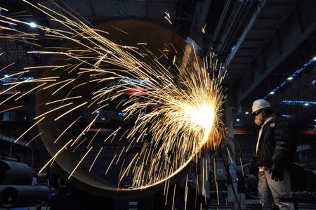 A worker of China National Offshore Oil Co (CNOOC) cuts steel structure for an offshore oil platform in Qingdao, Shandong province, China January 31, 2018. China Daily via REUTERS/Files