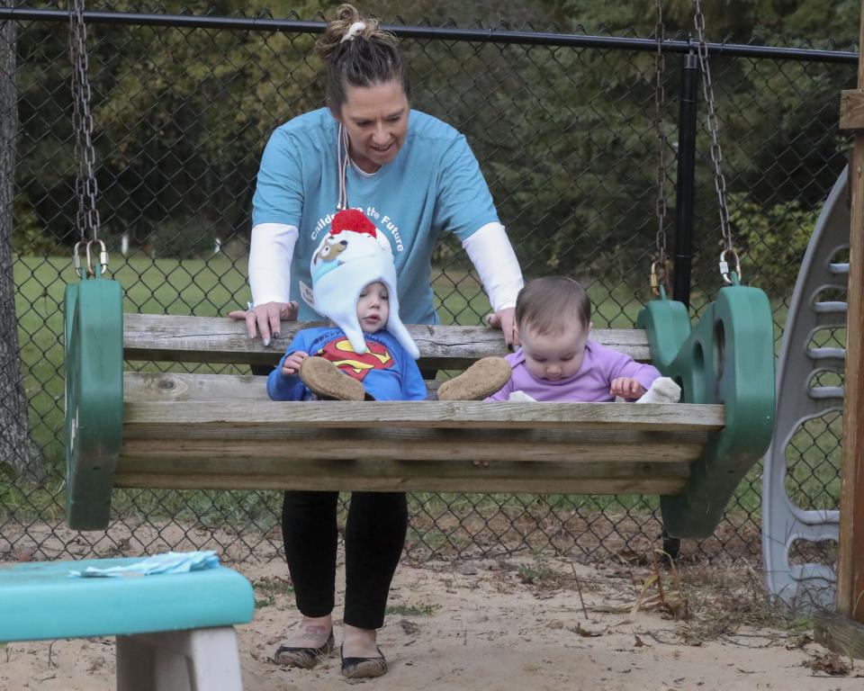 Jeannie Arndt pushes Ozzy Felts, 18 months, left, and Loren Fiegel, 11 months, on a swing on Oct. 5 at Little Racecar Daycare in Wisconsin Rapids. Arndt paid for fencing with funding received through a grant program that helps people in nine counties meet the requirements to become regulated child-care providers.