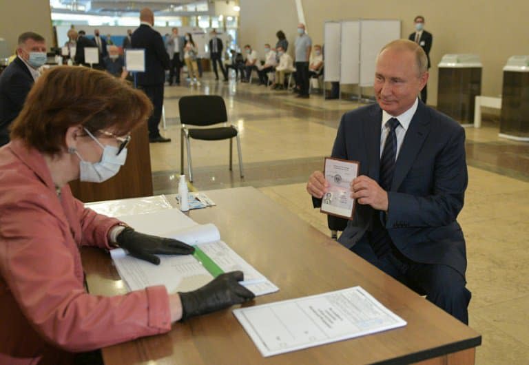 Le président de la Russie, Vladimir Poutine, montre son passeport à une membre d'une commission électorale pour participer au scrutin dans un bureau de vote de Moscou, le 1er juillet 2020 - Alexei Druzhinin © 2019 AFP