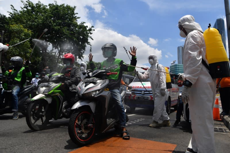 A worker sprays disinfectant on motorists, to prevent the spread of coronavirus disease (COVID-19) in Surabaya