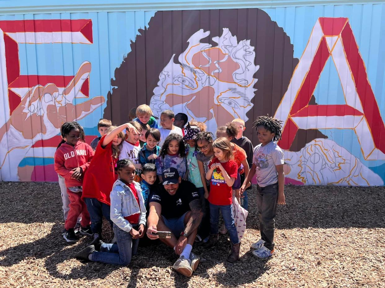 Artis Neo Medina taking a selfie with Read Elementary kids in front of the mural.