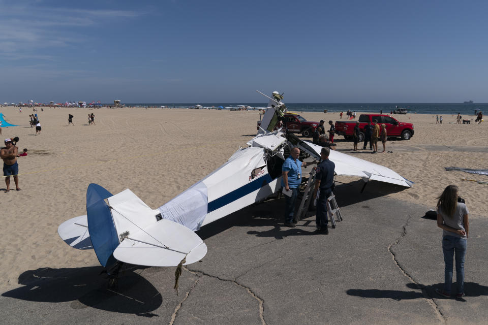 A small plane that was pulled from the water after it crashed into the ocean rests on the beach in Huntington Beach, Calif., Friday, July 22, 2022. The plane towing a banner crashed in the ocean Friday during a lifeguard competition that turned into a real-life rescue along the popular beach. (AP Photo/Jae C. Hong)