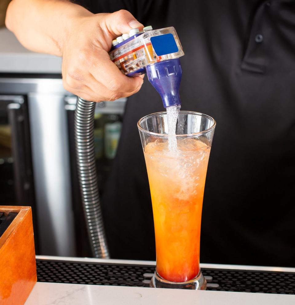 close up of someone using the soda gun to make a drink