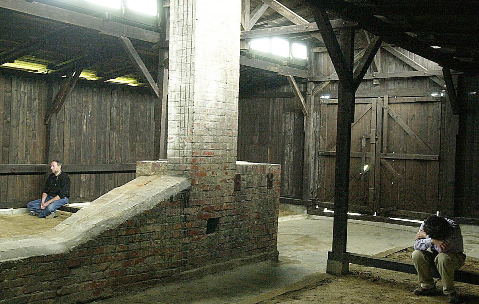 FILE - In this May 28, 2003 file photo, visitors sit inside a wooden barrack for inmates in Birkenau, a part of the former death camp of Auschwitz-Birkenau, where Nazi Germans killed some 1.5 million people, mostly Jews during World War II. Police and prosecutors in southern Poland were investigating on Wednesday, Oct. 6, 2021, English and German language graffiti found on the barracks of the former Nazi German death camp of Auschwitz-Birkenau. (AP Photo/Czarek Sokolowski, File)