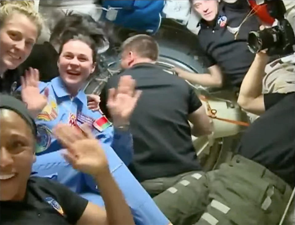 Vasilevskaya (left in blue flight suit) waves at a camera moments after floating into the International Space Station.  Dyson swims alongside her on the upper left with Jeanette Epps on the lower left.  / Credit: NASA TV