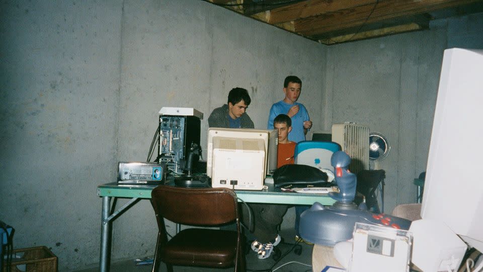 Many ofhe visuals in "LAN Party" are also an artifact of the wider trends happening at that point in time. Posters of hip-hop artist, 90s pin-ups and anime series, bubble furniture and baggy jeans can be spotted in the periphery. Or not, in the case of the sparse photo above, of gaming fans — and indoor fans — in Lee's Summit, Missouri in 2001. - Dane Oleson/Electronox/Courtesy Thames & Hudson