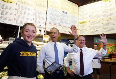 U.S. President Barack Obama and U.S. Rep. Gary Peters raise their hands in a vote whether restaurant worker Andrea Byl (L) should go live in France while ordering food at Zingerman's Deli in Ann Arbor, Michigan, April 2, 2014. REUTERS/Larry Downing