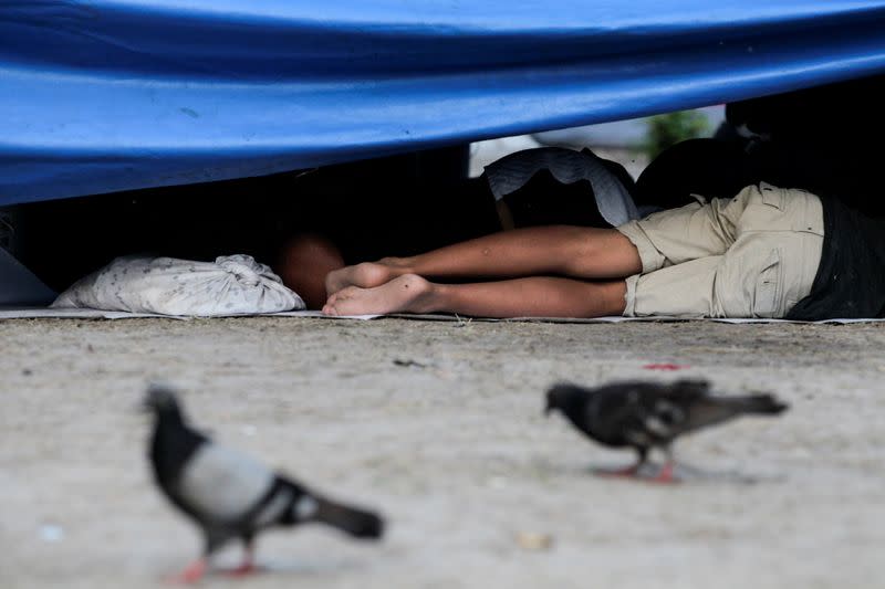 Un joven migrante solicitante de asilo, que fue aprehendido con sus padres y devuelto a México bajo el Título 42 después de cruzar la frontera de México a Estados Unidos, duerme en una plaza pública donde cientos de migrantes viven en tiendas de campaña, en Reynosa, México