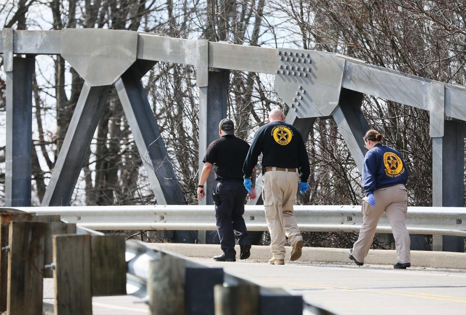 Authorities walk across the Middlebury Road bridge towards the Middlebury Trailhead entrance on Tuesday at near a taped-off area.