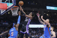 Sacramento Kings guard Keon Ellis (23) prepares to shoot between Oklahoma City Thunder guard Luguentz Dort (5) and forward Jaylin Williams (6) during the first half of an NBA basketball game Tuesday, April 9, 2024, in Oklahoma City. (AP Photo/Nate Billings)