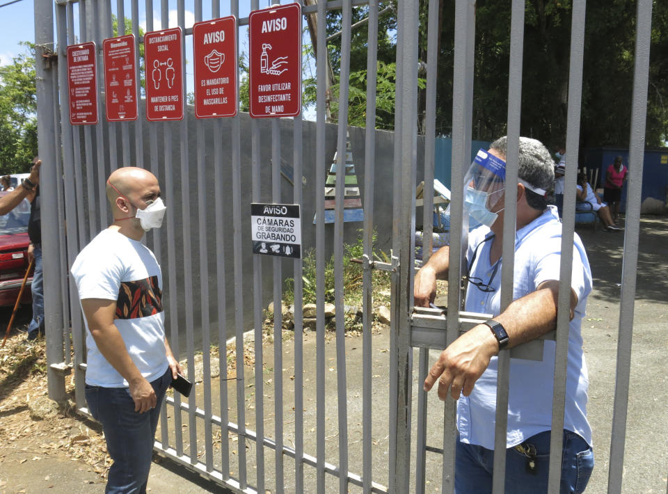 Un funcionario electoral, a la derecha, grita a un votante que no han llegado las papeletas, en un centro de votación en Carolina, Puerto Rico, el domingo 9 de agosto de 2020. (AP Foto/Dánica Coto)