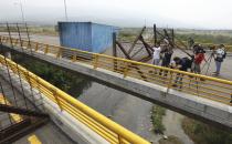 Journalists record a fuel tanker, cargo trailers and makeshift fencing, used as barricades by Venezuelan authorities attempting to block humanitarian aid entering from Colombia on the Tienditas International Bridge that links the two countries as seen from the outskirts of Cucuta, Colombia, Wednesday, Feb. 6, 2019. Immigration authorities say the Venezuelan National Guard built the roadblock a day earlier. (AP Photo/Fernando Vergara)