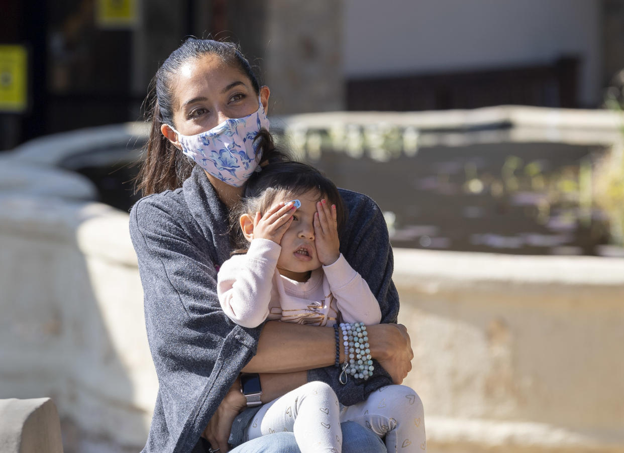 A girl covers up as she listens to a celebratory ringing of the bells with her mom in San Juan Capistrano, CA on February 4, 2021. (Photo by Paul Bersebach/MediaNews Group/Orange County Register via Getty Images)