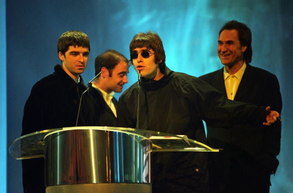 Oasis receive their 'Best British Newcomer' award from Kinks lead singer, Ray Davies. (L/R) Noel Gallagher, Paul McGuigan, Liam Gallagher, and Ray Davies.   (Photo by Fiona Hanson - PA Images/PA Images via Getty Images)